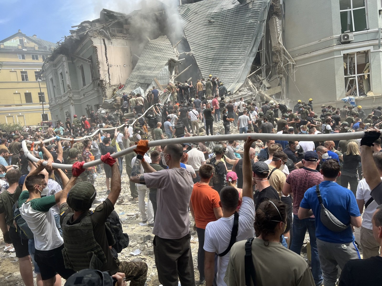 Kyiv residents who came to help clear the debris hold a fire hose above their heads. Kyiv, July 8, 2024. Photo by the author.